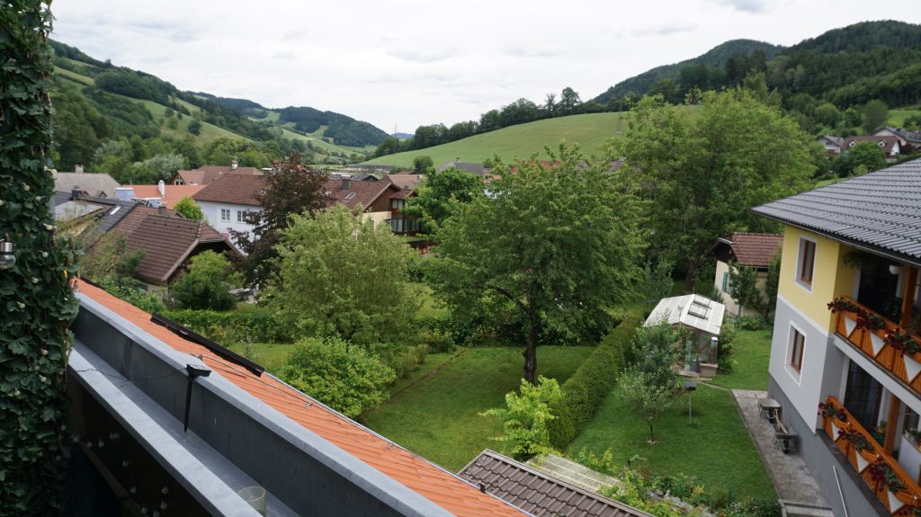 Blick über ein Dorf in den Hügeln mit Häusern und grünen Bäumen