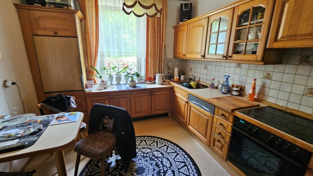 Küche mit Holzküchenzeile, Esstisch und Fenster mit Pflanzen
