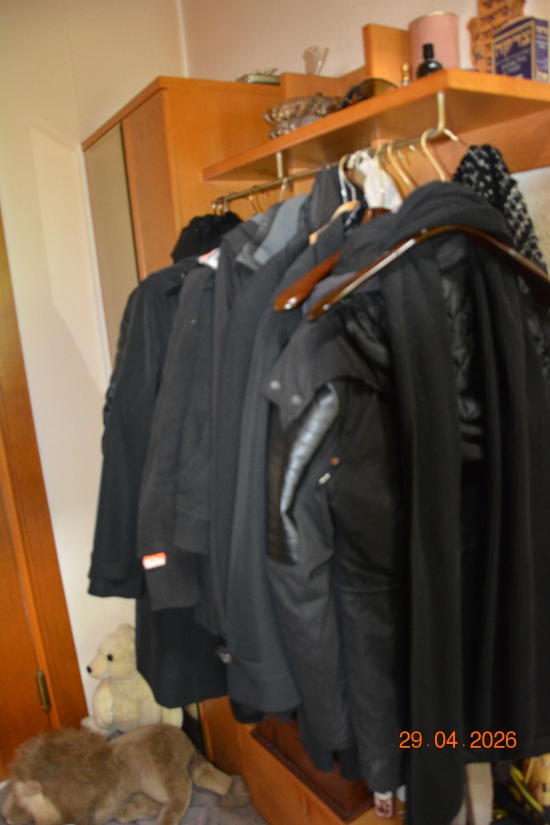 Garderobe mit Jacken und Teddybär vor Holzmöbel
