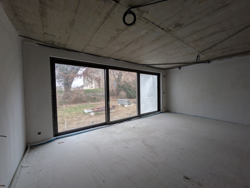 Leerer Raum mit Betonwänden und -decke, großem Fenster mit Blick ins Freie