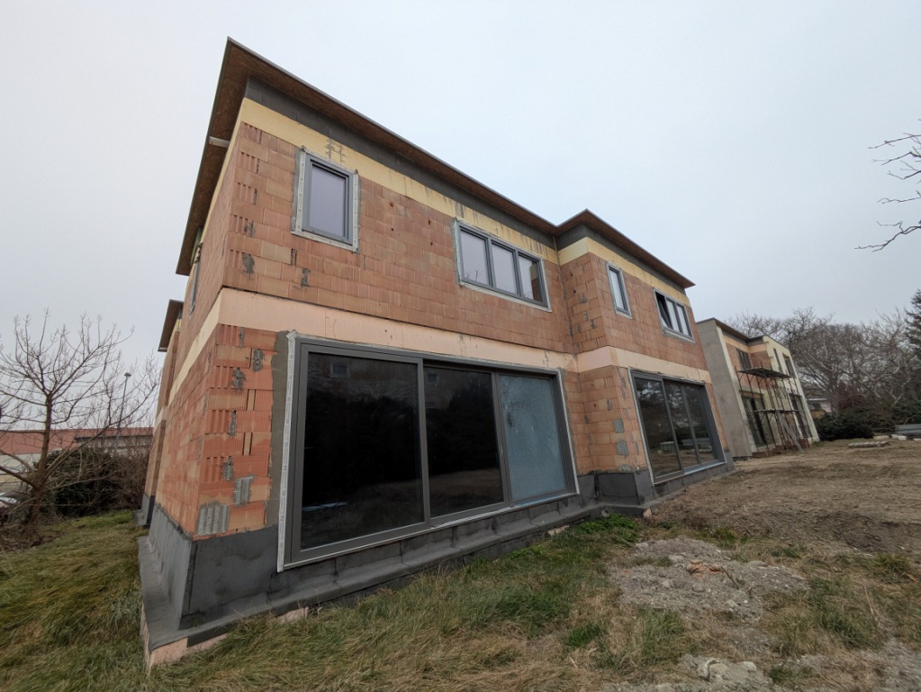 Neubau in Österreich: Ziegelwand mit Fenstern und Dachvorsprung im Rohbau