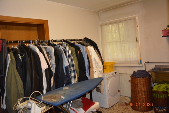 Kleiderständer mit Kleidung, Bügelbrett, Waschmaschine und Wäschekorb