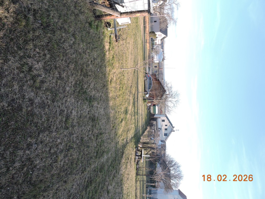 Wiese mit Schatten und Häusern in der Ferne, 18.02.2026