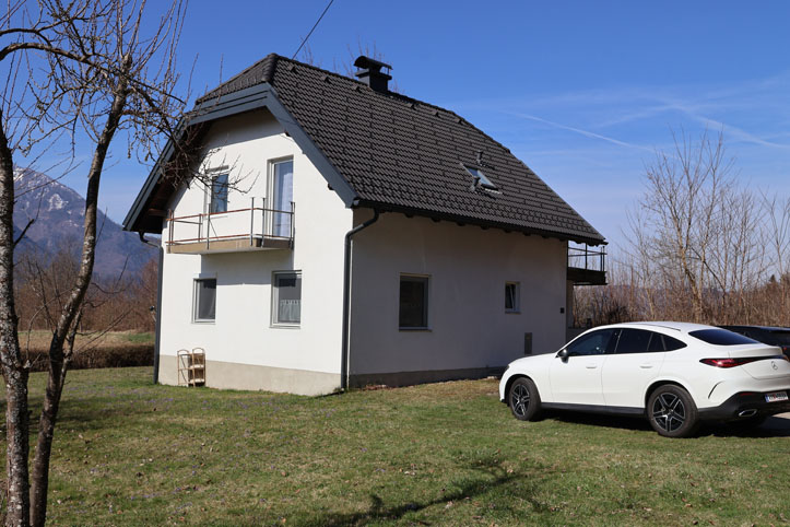 Weißes Haus mit Balkon und weißem Mercedes-Coupé auf einem Rasen in Österreich