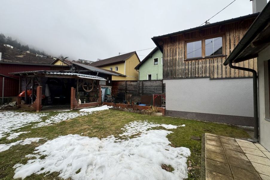 Ländliches Anwesen mit Holzhäusern und Schneeresten im Garten