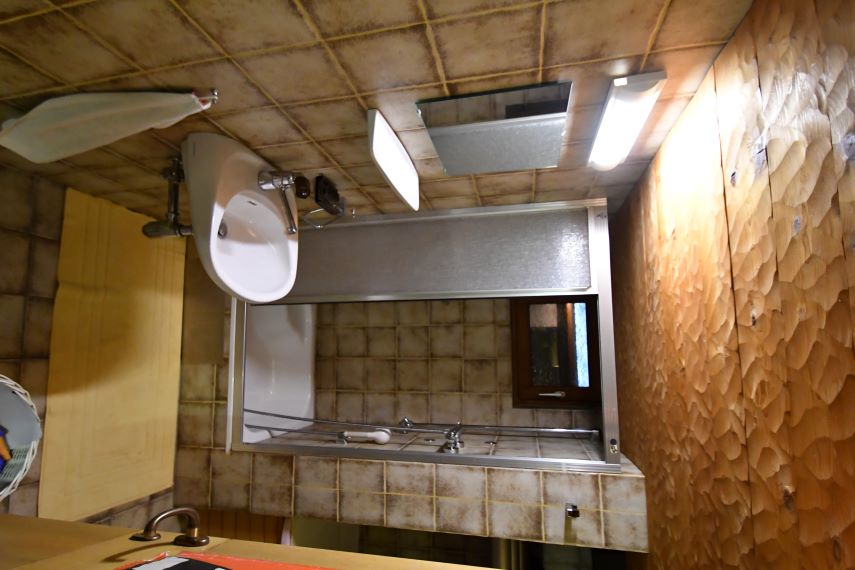 Badezimmer mit Waschbecken, Spiegel und Holzwandverkleidung