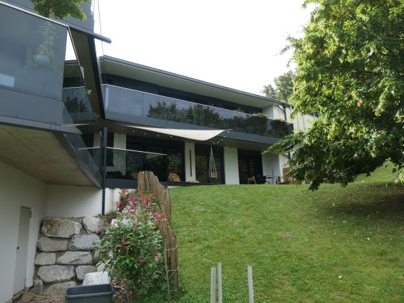 Moderne Villa mit Glasbalkonen und Garten in Hanglage