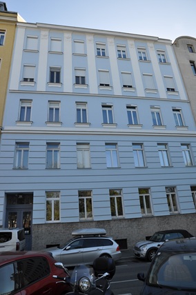 Wiener Wohnhaus mit blauer Fassade und Autos davor