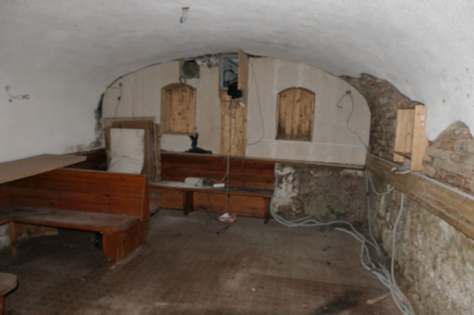 Holzbank in einem Kellerraum mit Gewölbedecke und freiliegenden Kabeln