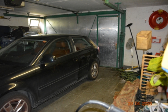 Schwarzer Audi A3 in einer Garage mit Garagentor und verschiedenen Gegenständen