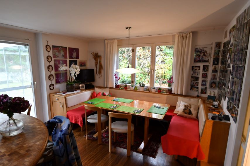 Essbereich mit Eckbank, Holztisch und vielen Fotos an der Wand