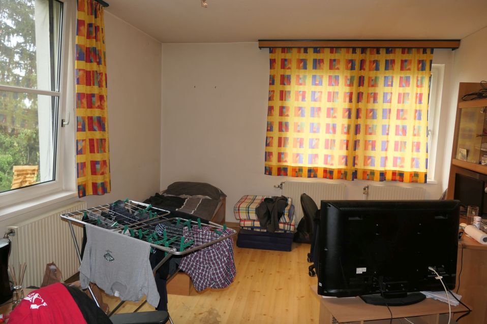 Schlafzimmer mit Wäscheständer, Bett und Fernseher