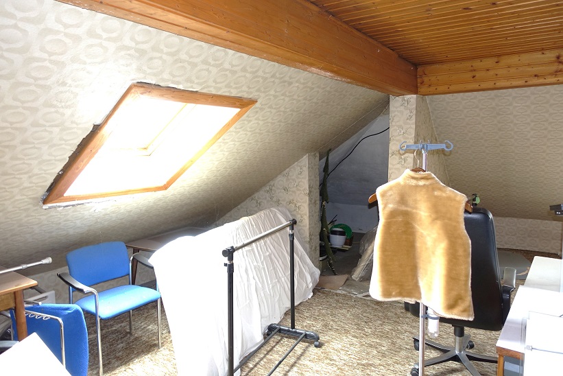Dachboden mit Dachfenster, Kleiderständer mit Weste, blauen Stühlen und Schreibtisch