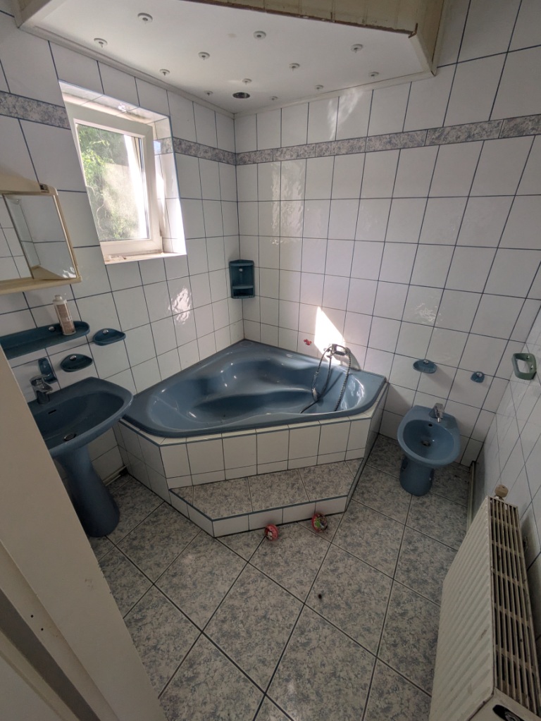 Badezimmer mit Eckbadewanne, Waschbecken und Bidet in blauer Keramik