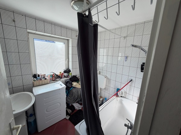 Badezimmer mit Waschmaschine, Waschbecken, Badewanne und Duschvorhang