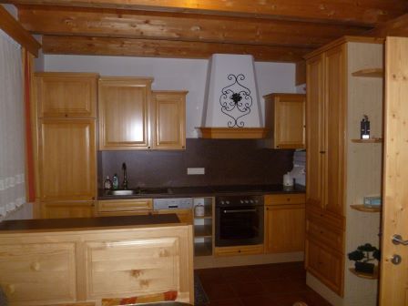 Holzküche mit Einbaugeräten und Kaminhaube mit Ziergitter
