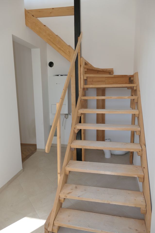 Holztreppe mit weißem Kamin und Heizung im Hintergrund