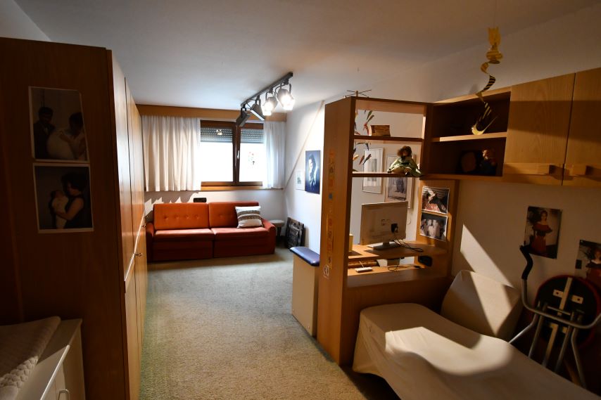 Schlafzimmer mit orangefarbenem Sofa, Schreibtisch und Bett
