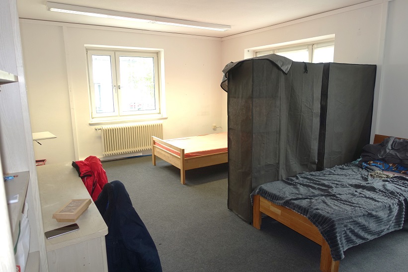 Schlafzimmer mit zwei Betten, einem Schreibtisch und einem Kleiderschrank aus Stoff