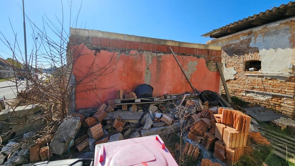 Abriss, Ziegel und Bauschutt vor einer verfallenen Wand mit rotem Putz