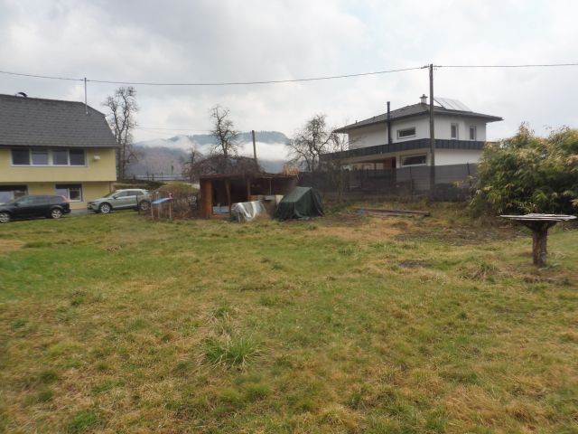 Zwei Autos parken vor gelbem Haus, daneben ein Schuppen und ein Haus mit Solaranlage