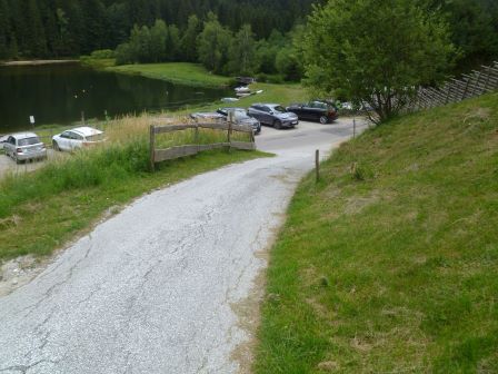 Parkplatz am Bergsee mit Autos und Holzzaun in der Steiermark