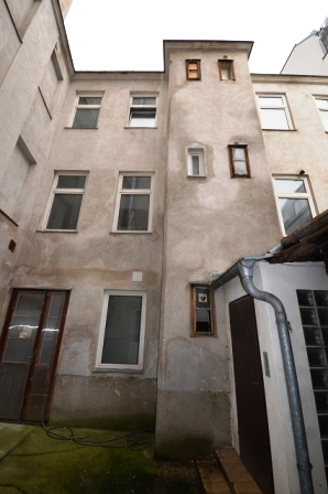 Hinterhof mit mehreren Fenstern und einer Tür, Fassade mit Putz