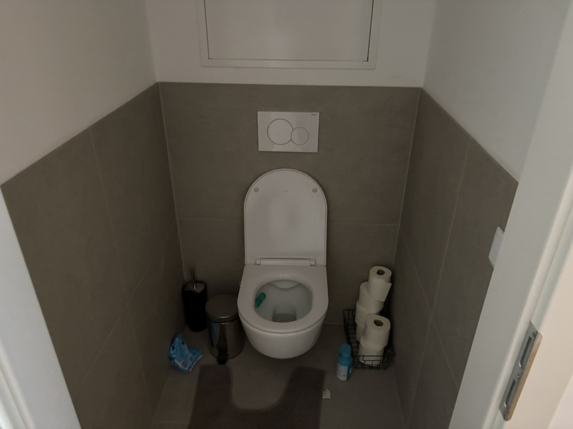 Toilette mit Spülkasten und Toilettenpapier im Badezimmer