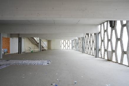 Betonbau mit Wabenmusterfenstern und Treppenaufgang in einem unfertigen Gebäude.