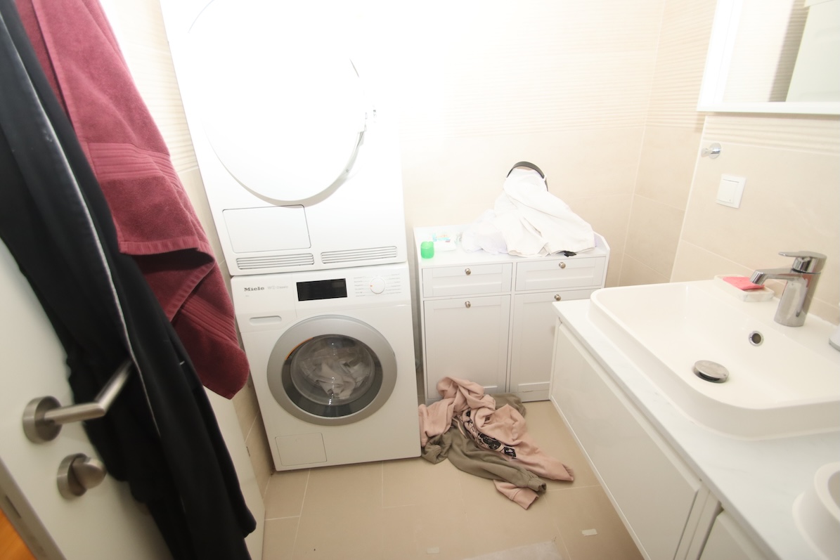 Waschküche mit Miele Waschmaschine, Trockner, Waschbecken und Kleidung