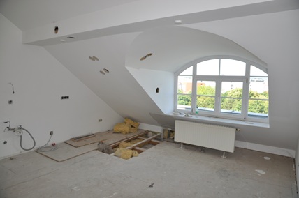 Rohbau eines Dachbodens mit offenem Boden, Dämmung und Rundbogenfenster
