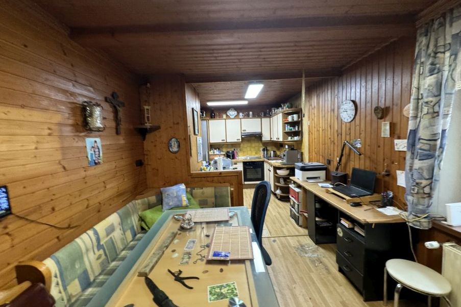 Holzvertäfelte Stube mit Sitzbank, Esstisch und Arbeitsplatz mit Laptop und Drucker