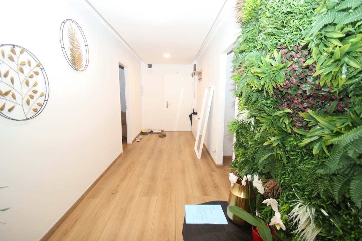 Flur mit grüner Pflanzenwand und Wanddeko in Goldtönen