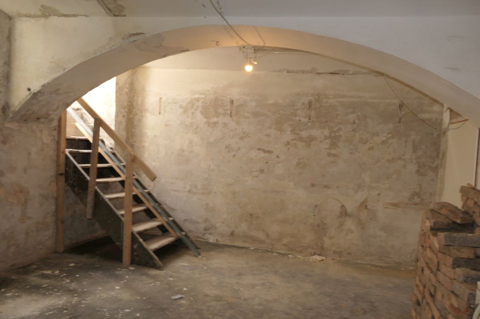Keller mit Holztreppe und Ziegelstapel, Stuckdecke, grober Putz