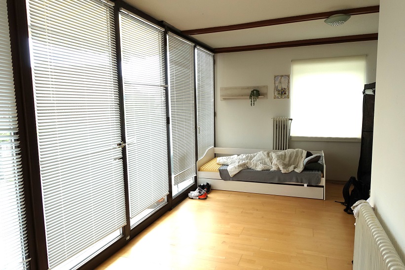 Schlafzimmer mit Bett und Jalousien, Holzboden, Heizkörper
