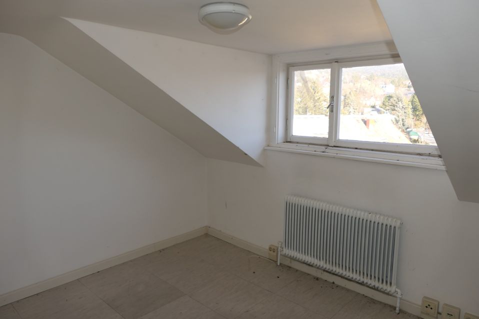 Dachgeschosswohnung mit Schrägwand, Heizkörper und Fenster mit Blick auf die Umgebung