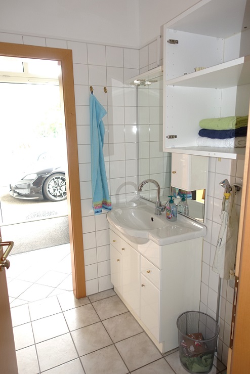 Badezimmer mit Waschbecken und Blick auf ein Auto in der Garage
