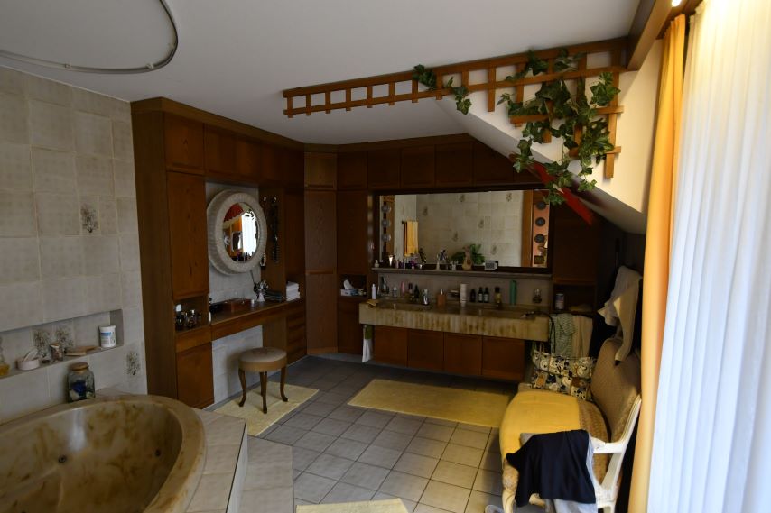 Badezimmer mit Marmorwanne, Waschtisch, Spiegel und Sitzmöbeln