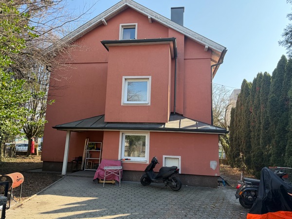 Haus mit rotem Anstrich, Roller und Bäume an der Seite