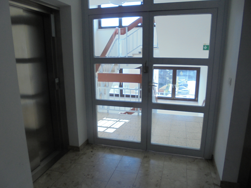 Treppenhaus mit Glastür und Aufzug in einem Gebäude