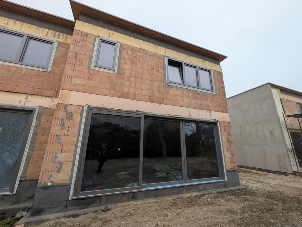 Hausbau in Österreich: Ziegelbau mit Fenstern und Schiebetür im Rohbauzustand.