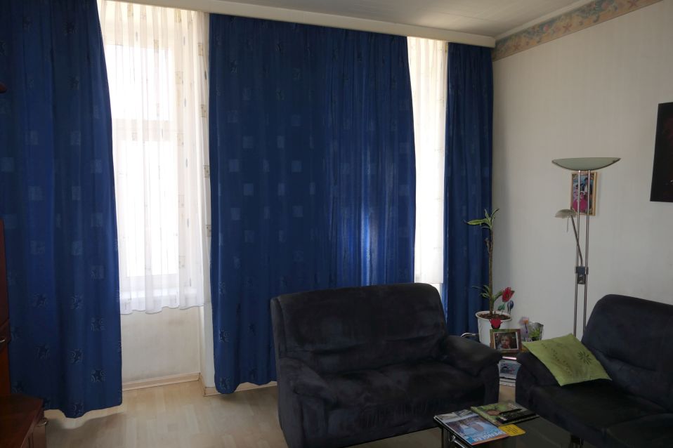 Wohnzimmer mit blauen Vorhängen, zwei Sofas, Stehlampe und Bilderrahmen