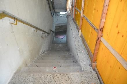 Betonstiege mit Handlauf und gelber Bauwand auf einer Baustelle in Österreich