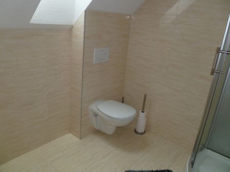 WC-Schüssel mit Spülkasten und Bürste in einem gefliesten Badezimmer