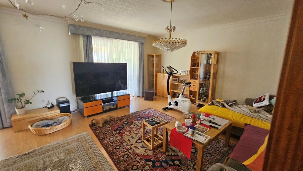Wohnzimmer mit Fitnessrad, Hund und Fernseher