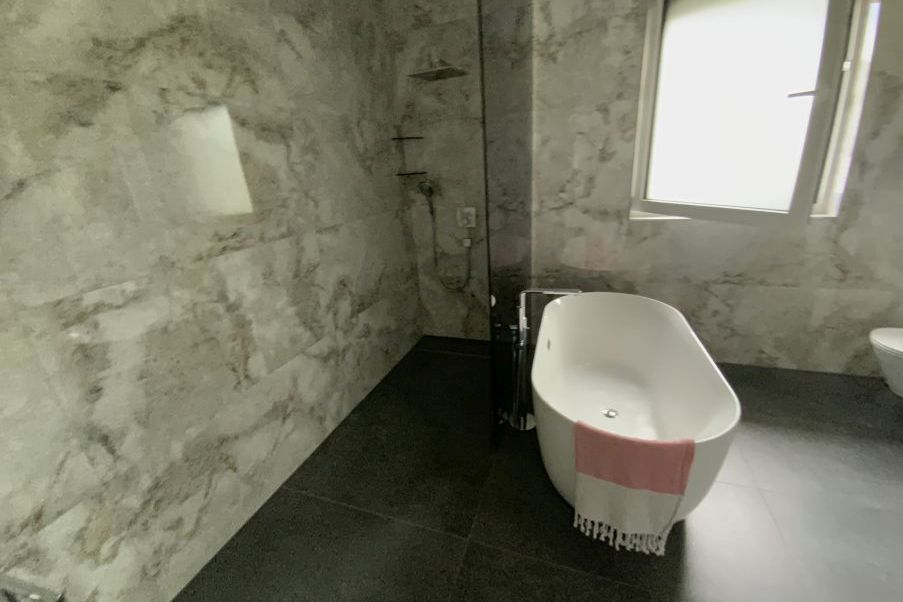Freistehende Badewanne mit rosa Handtuch und Duschkabine in modernem Badezimmer