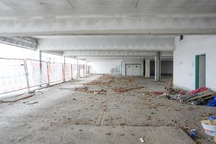 Baustelle mit Bauschutt und Absperrgittern in einem leeren Gebäude
