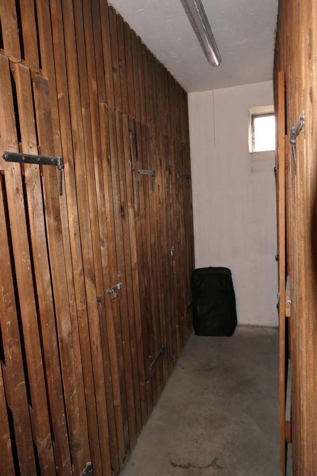 Holzverschläge mit Haken und Riegeln, dunkler Sack und kleines Fenster im Gang