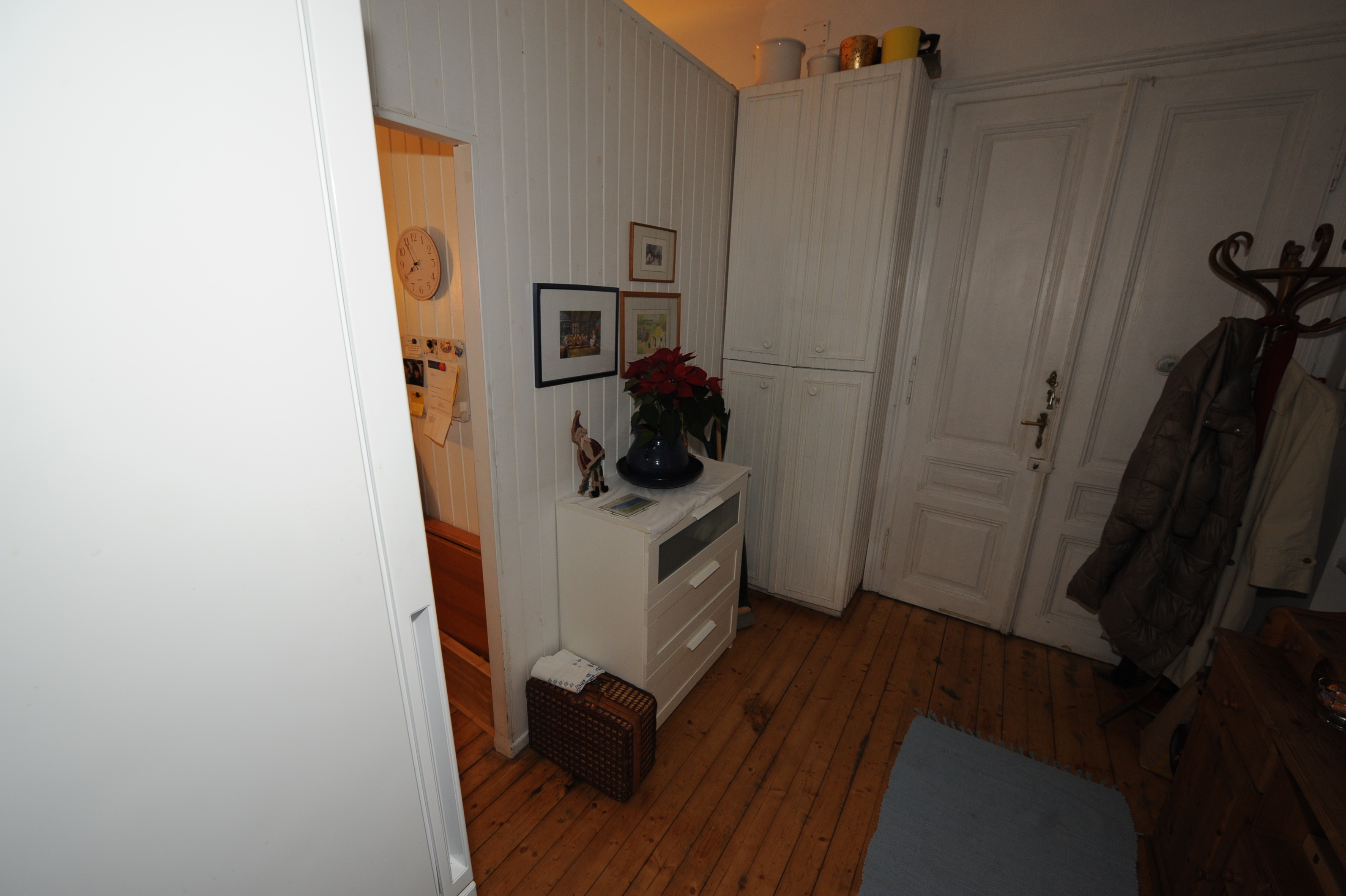 Garderobe mit Kleidung und Kommode in einem Flur mit Holzboden.
