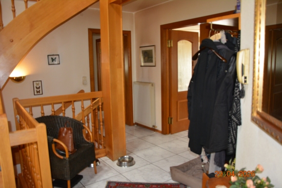 Vorraum mit Holztreppe, Sesseln, Kleidung und Tür zum Garten